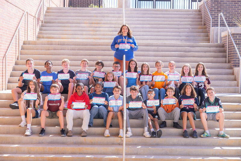 teens sitting on steps in school hallway holding certificates