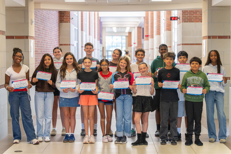 teens standing in hallway at school holding certificates