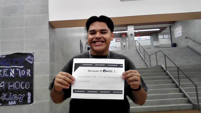teen boy standing in school hallway holding certificate