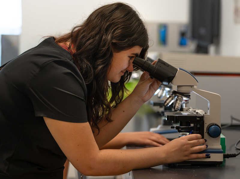 teen girl looking through microscope on table