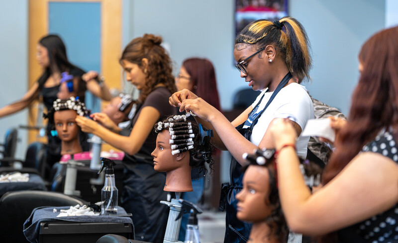 teen girls giving perms to mannequins in cosmetology salon