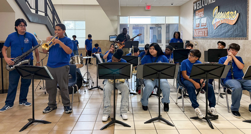 middle school students playing band instruments in school hallway