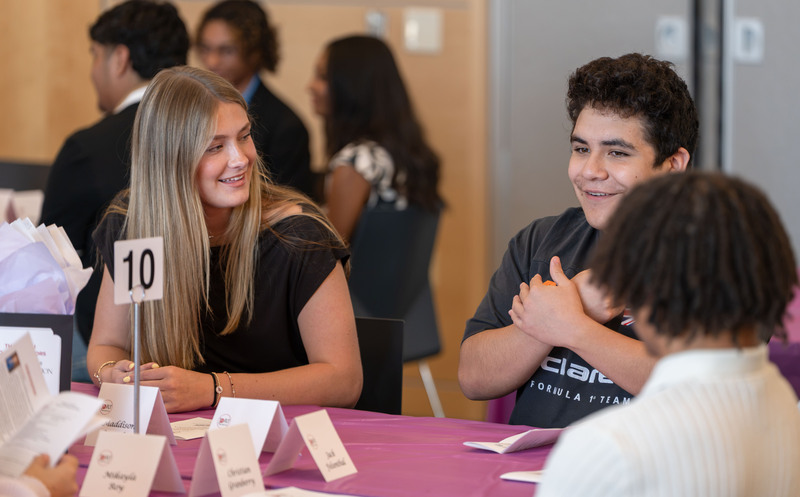 teenagers sitting at a table talking to each other