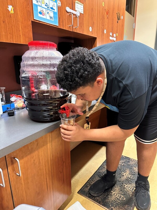 teen boy fills cup with tea from large jug
