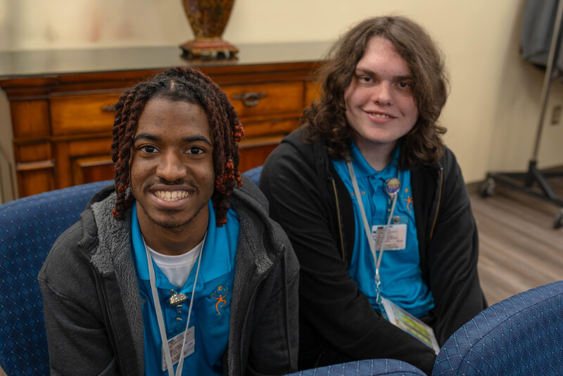 two teen boys sitting in a chair listening to speaker