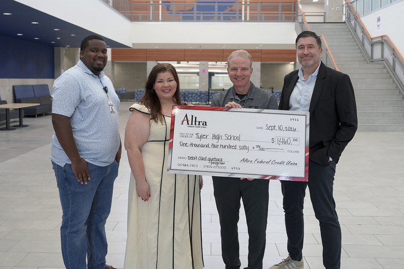 men and women standing in school hallway holding giant check for $1460