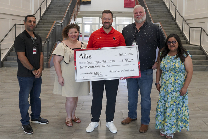 men and women standing in school hallway holding giant check for $4400