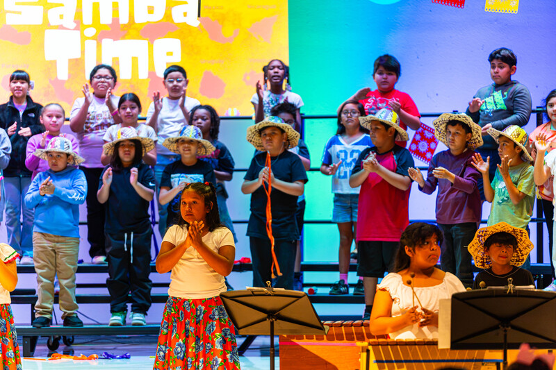 elementary age boys and girls in Hispanic dress performing on stage