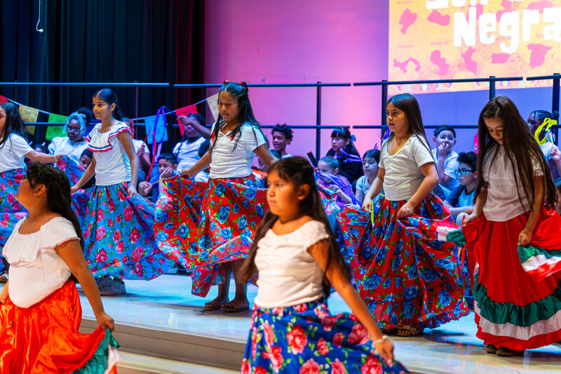 elementary age girls in traditional Hispanic dress dancing on stage