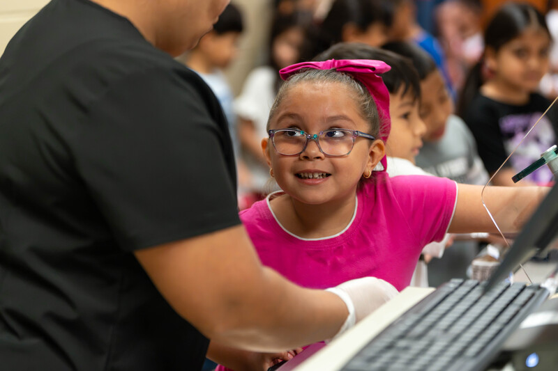 young girl wearing glasses smiles at woman as she pays for her school lunch