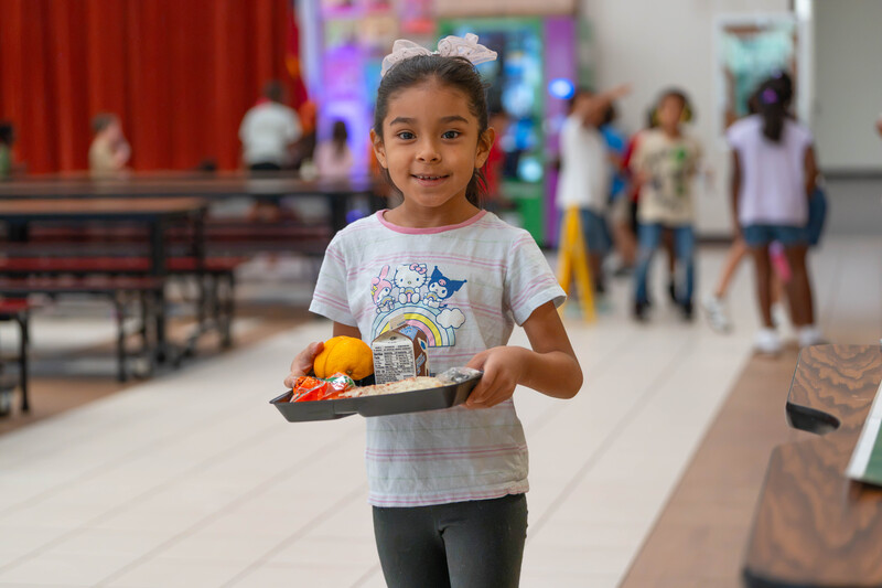 young girl carring lunch tray in cafeteria