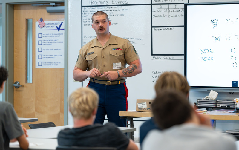 US Marine in uniform talking to high school students in classroom
