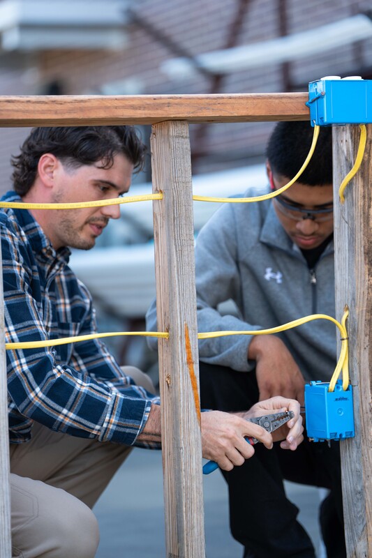 man and teen boy working on electrical wiring along 2x4s