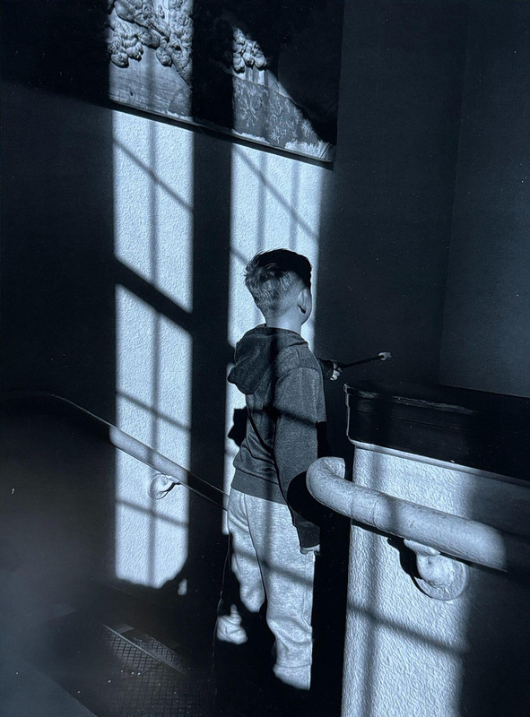 view from behind of a small boy standing at the top of a stairwell looking down