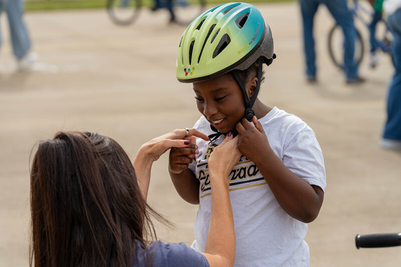 woman helping young girl adjust her bike helmet