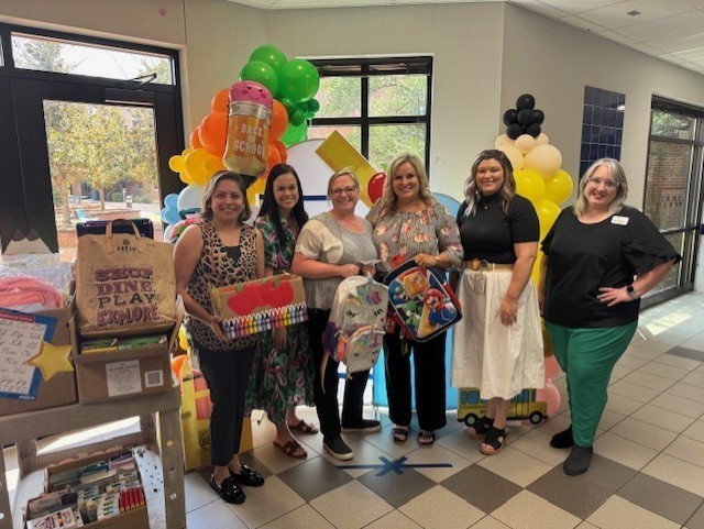 women standing next to cart with school supplies