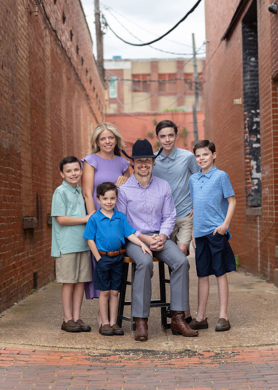 woman and man with their four sons in an alley with brick walls and streets