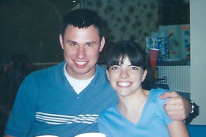 teen boy and girl wearing blue shirts with their arms around each other