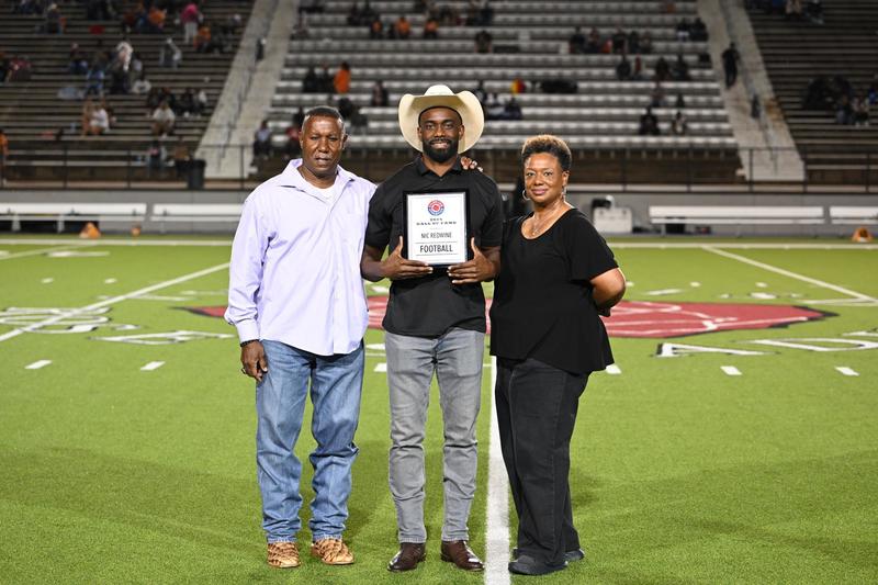 two African American men and a woman standing on football field