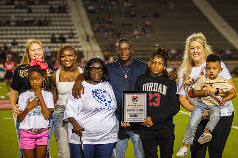 family standing on football field holding a plaque