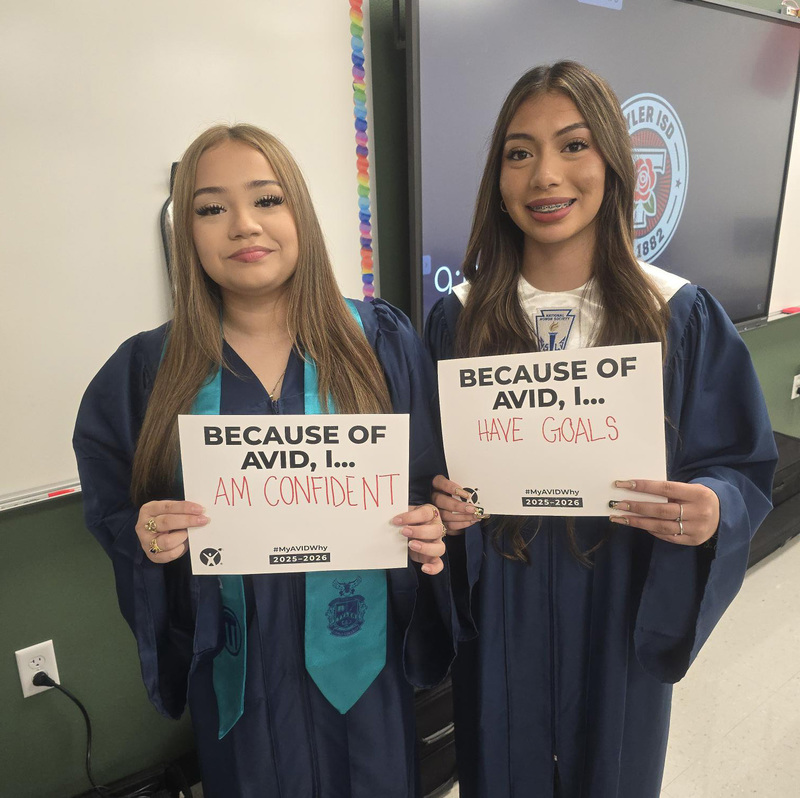 two teen girls holding signs "Because of AVID I..."