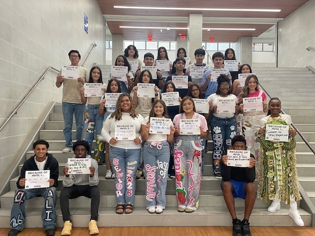 high school students standing on staircase holding signs