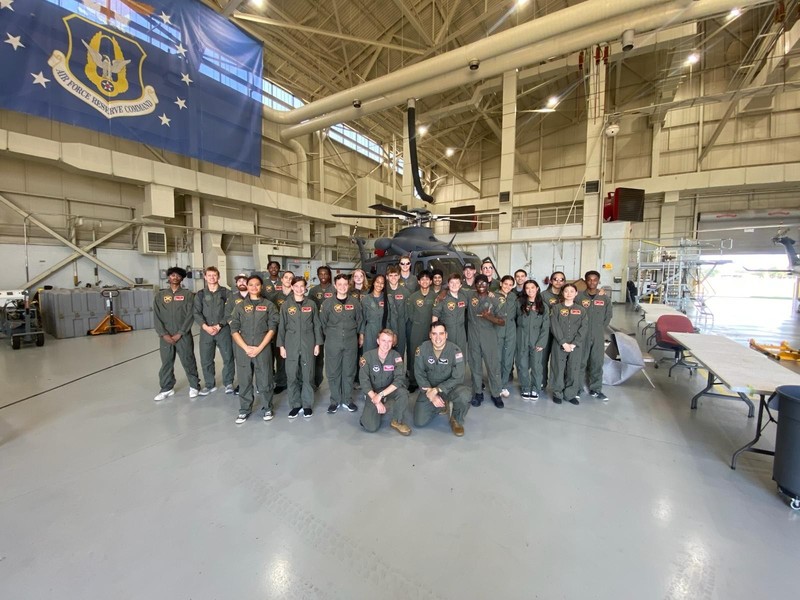 group of teens standing in front of helicopter
