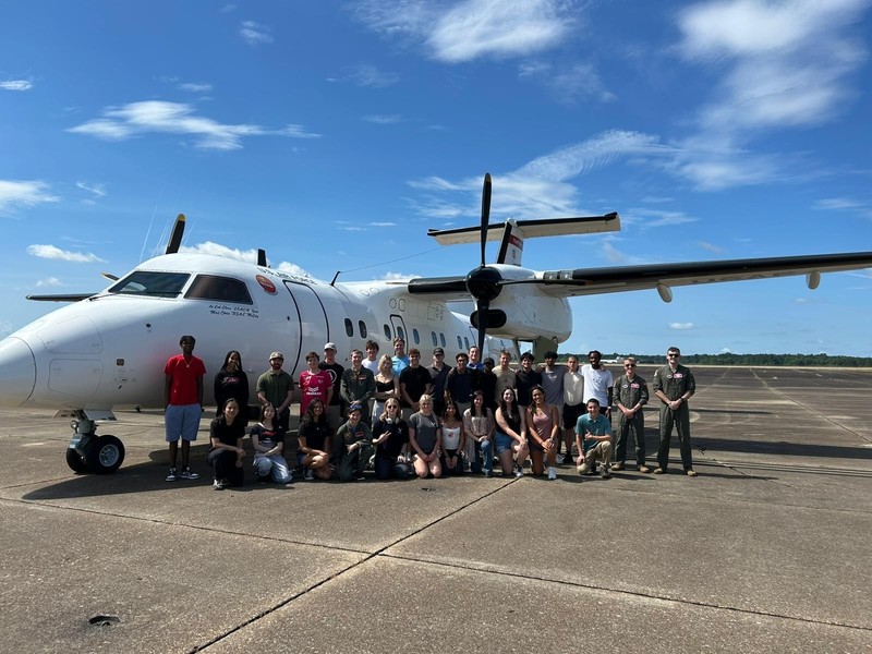 group of teens gathered beside an airplane