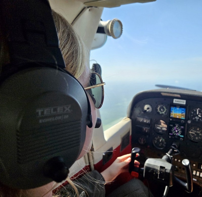 view from behind a pilot in the air holding the handles in airplane cockpit