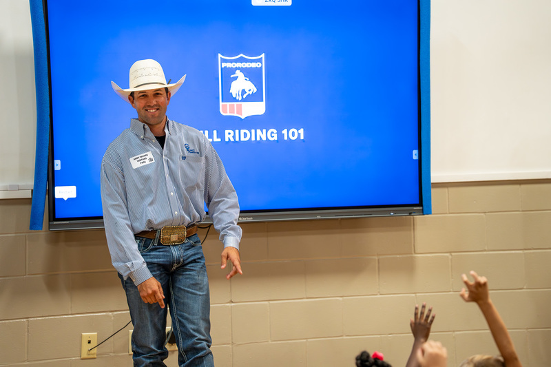 man in cowboy hat standing in front of video screen
