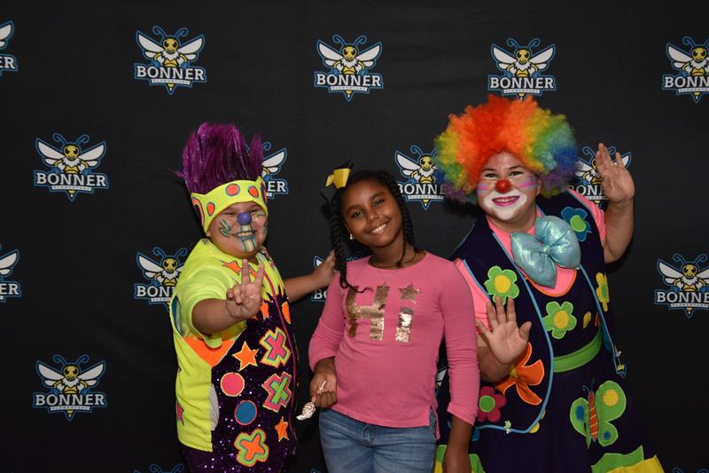 young girl between two kids dressed as clowns