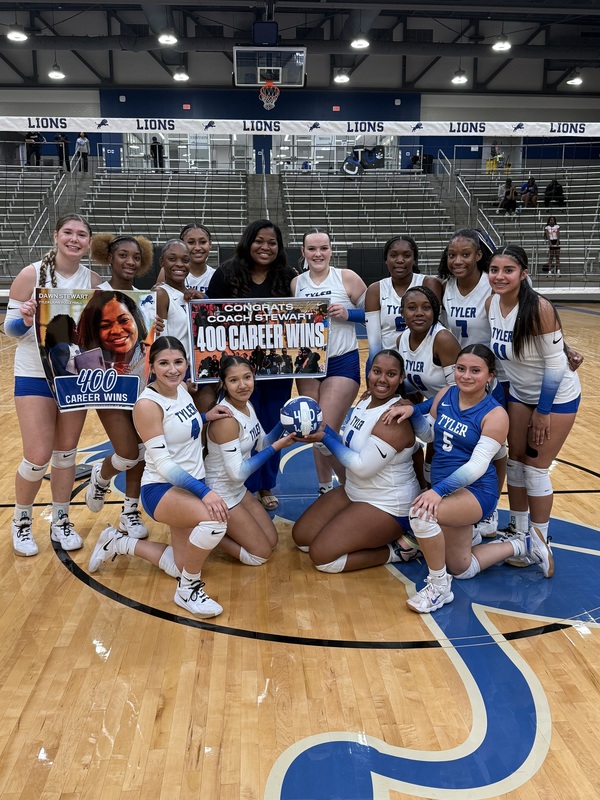 high school volleyball players in middle of gym floor with their coach