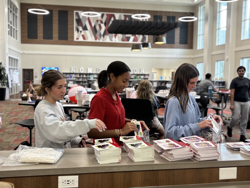 high school girls in a library holding up book packets