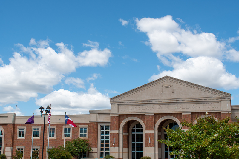 brick school building with US and Texas flags flying in front