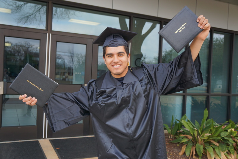 teen boy wearing black cap & gown holding two diplomas