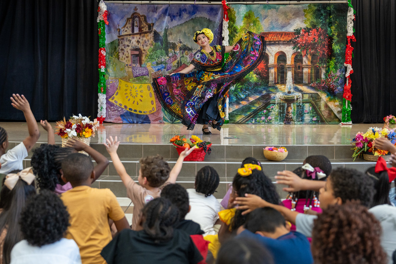 woman in traditional Hispanic dress dancing on stage