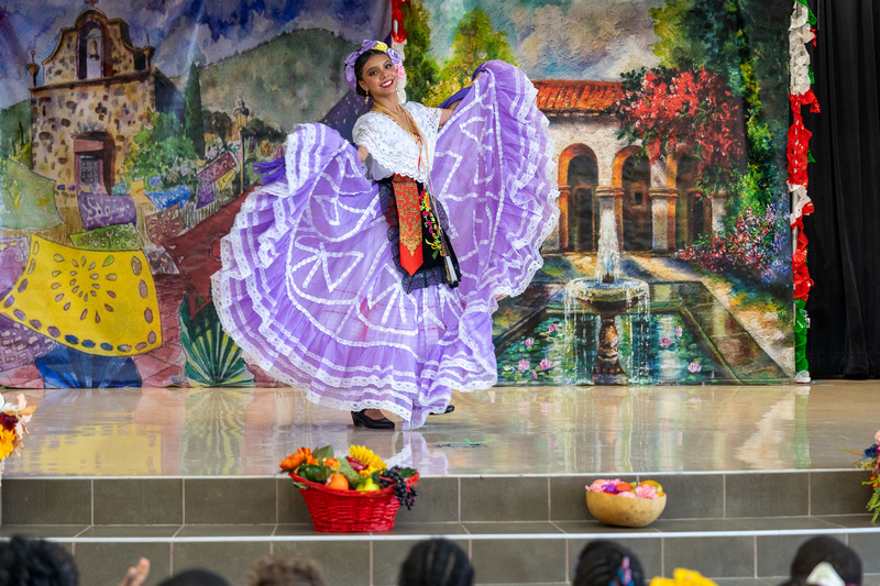 woman in traditional Hispanic dress dancing on stage