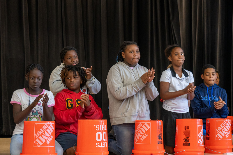 elementary age kids playing drums on Home Depot buckets