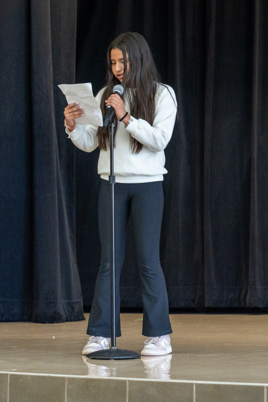 elementary age girl talking into microphone on stage