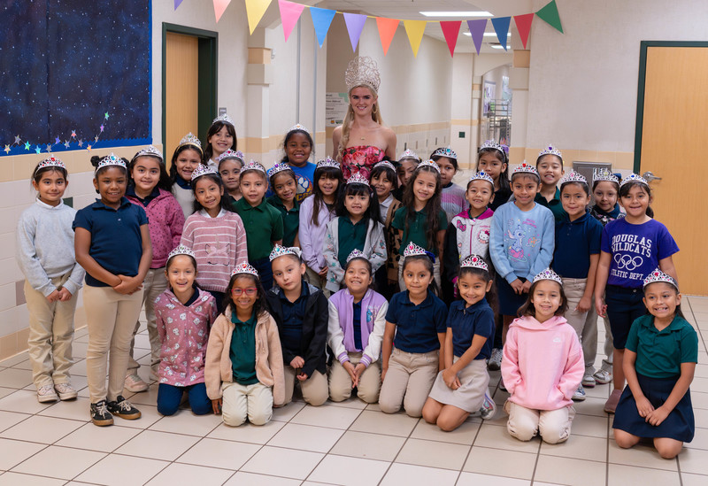 teen girl wearing crown standing behind elementary age girls wearing crowns