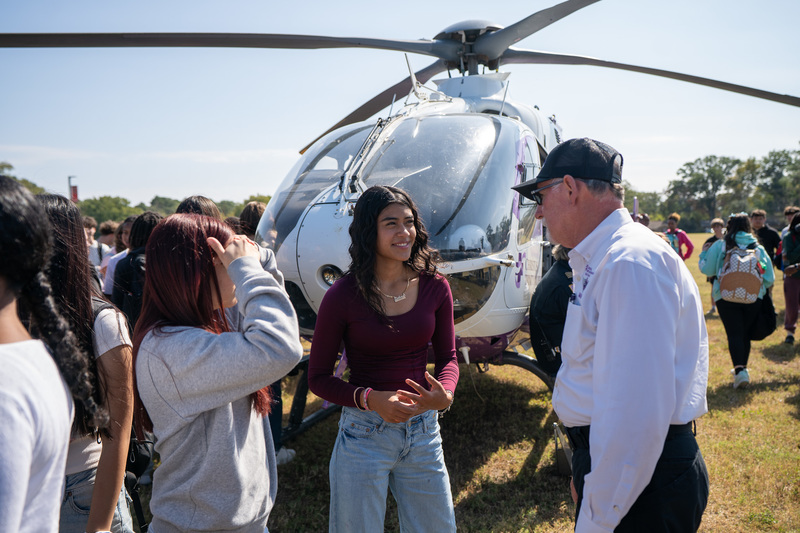 teens talk to paramedic in front of helicopter
