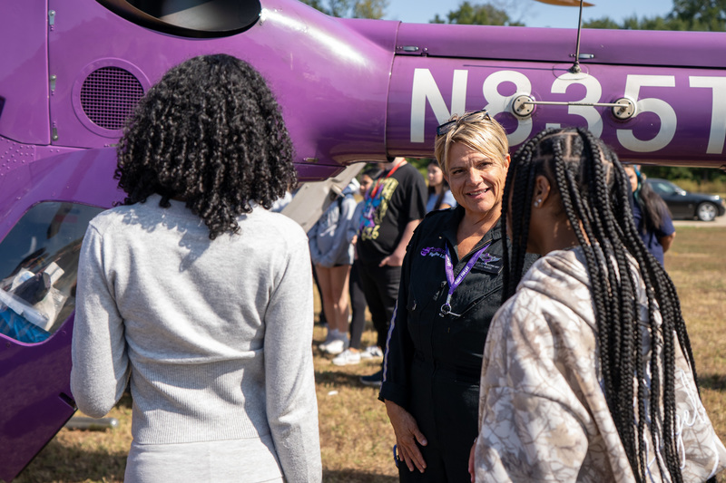 teens talk to paramedic in front of helicopter