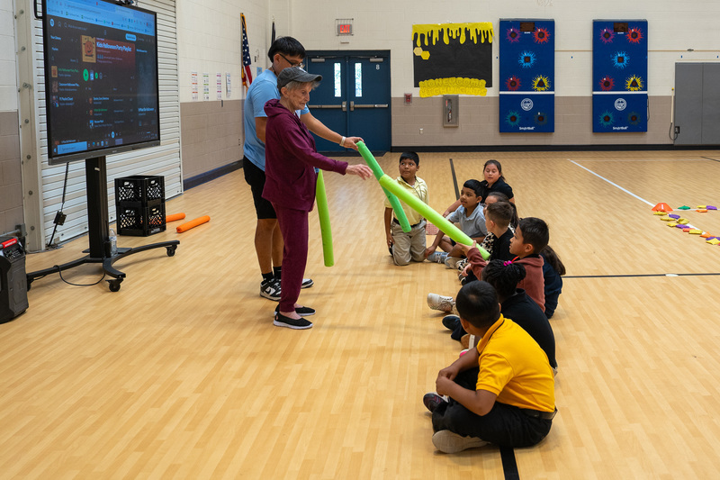 elderly woman helping kids in gym