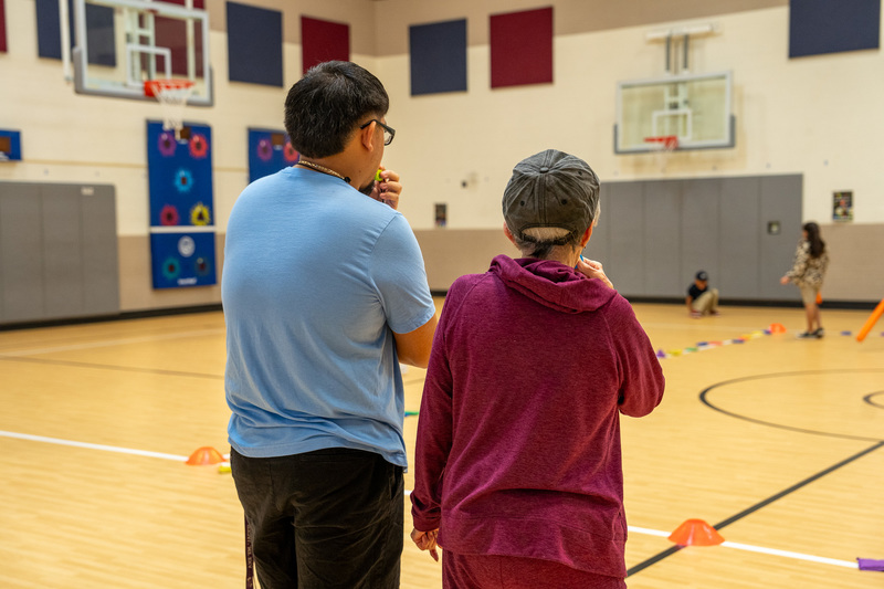 elderly woman standing next to man in gym