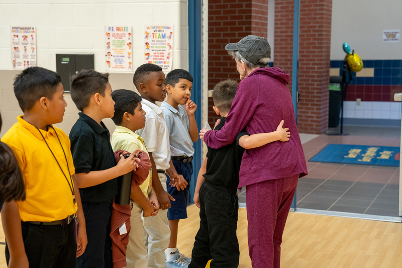 elderly woman hugging kids in a gym