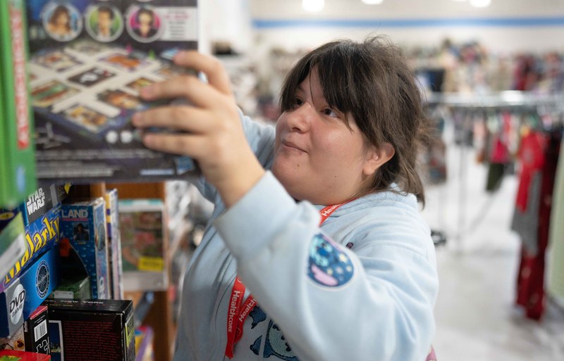 teen girl putting puzzle on shelf in store