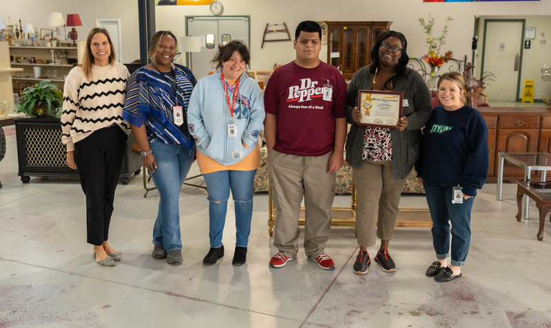 men and women in group holding plaque