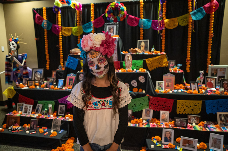 elementary age girl with face painted standing in front of ofrenda