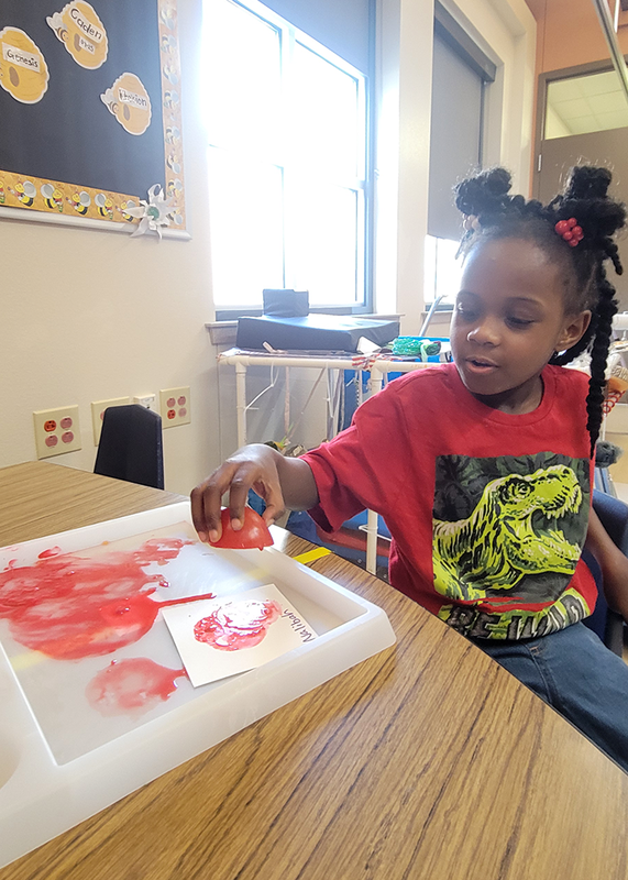 young girl holding sliced tomato