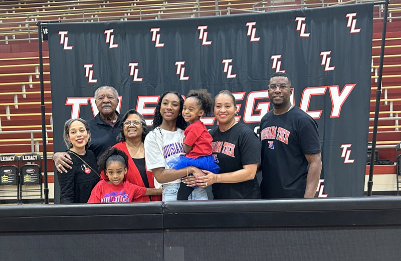 teen girl and her family stand in front of Tyler Legacy sign in gym